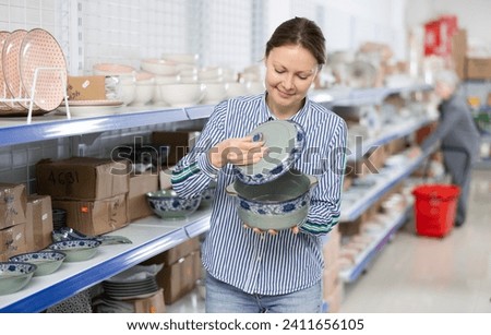 In the store, the customer chooses a soup tureen. A customer at a home improvement store buys dishes for a festive dinner with a large number of guests. Royalty-Free Stock Photo #2411656105