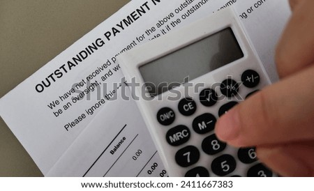 Financial debt concept. A person pressing a calculator placed above a letter with heading Outstanding Payment  Royalty-Free Stock Photo #2411667383