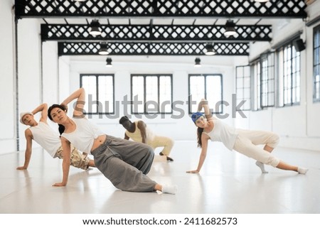 Stylish asian woman studying movement of contemporary dance in classroom with her friends