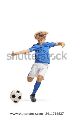 Boy in a football kit kicking a ball isolated on white background Royalty-Free Stock Photo #2411716537