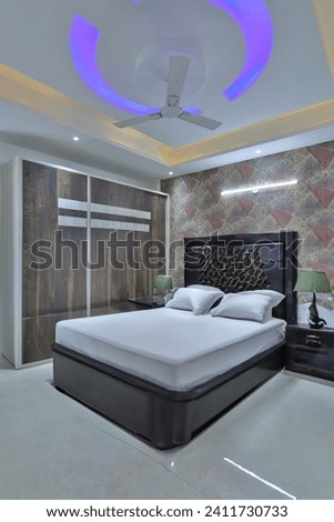 Portrait shot of a fully furnished bedroom with bed, wardrobe, side table, lamp and fan it in Royalty-Free Stock Photo #2411730733