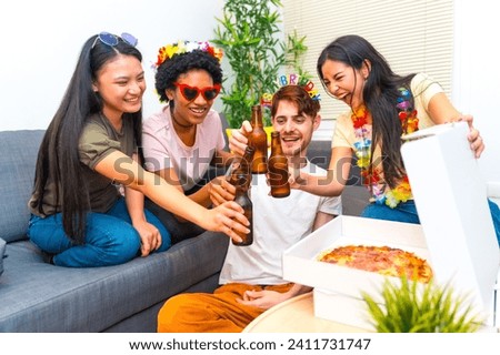Multi-ethnic happy friends toasting with beer during a birthday party at home