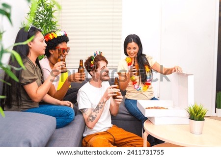 Happy multi-ethnic friends celebrating birthday party at home eating pizza and drinking beer