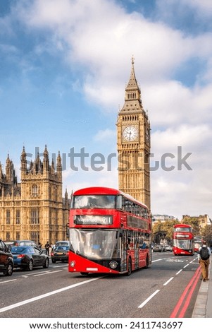 Big Ben with typical red buses on the bridge in London, England, UK Royalty-Free Stock Photo #2411743697