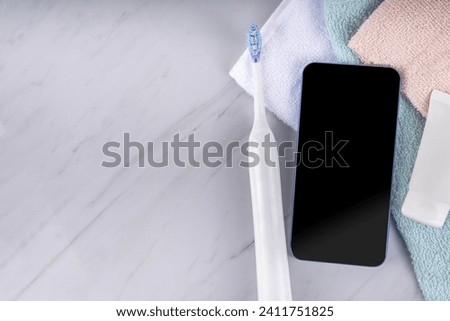 Electric Toothbrushes concept. Ultrasonic tooth brush with smartphone, with cosmetics bottles, stack of towels, toothpaste and phone. Female girl hands in pic. Modern dental care technology