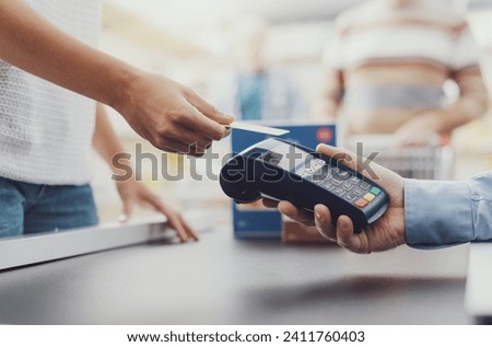 Woman purchasing food at the supermarket and paying with a credit card, the cashier is holding the POS terminal, hands close up Royalty-Free Stock Photo #2411760403