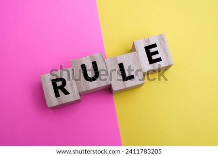 A wooden block with word “RULE” on it