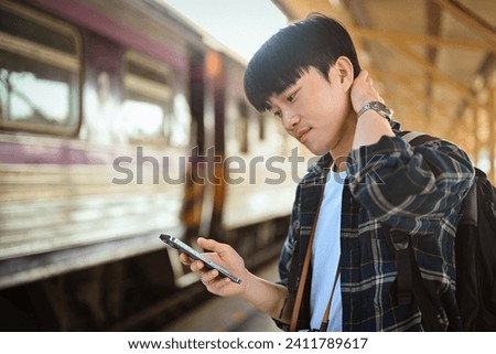 Handsome male traveler checking timetable train schedule for trip with application on smartphone