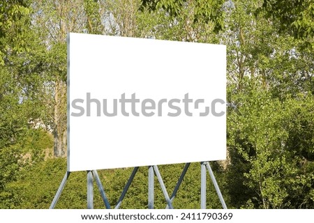 Blank advertising signboard with trees on background - concept with copy space for text inserting  Royalty-Free Stock Photo #2411790369