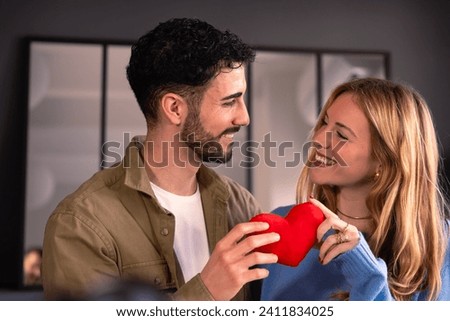 Valentine's Day. young couple look at each other affectionately while holding a heart. Royalty-Free Stock Photo #2411834025