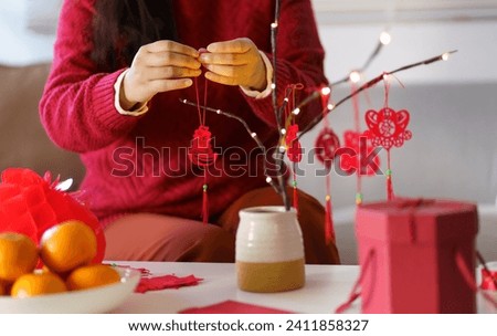 Asian Woman decorated house for Chinese New Year Celebrations. putting traditional pendant to the Chinese Lunar New Year for good luck. Chinese word means blessing. Royalty-Free Stock Photo #2411858327