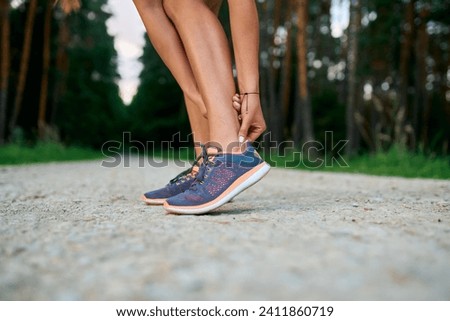 Close-up of female runner touching achilles tendon. Achilles tendonitis injury  Royalty-Free Stock Photo #2411860719