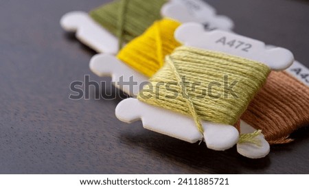 Close-Up of Green, Beige, and Yellow Cotton Floss Threads on Plastic Bobbins Royalty-Free Stock Photo #2411885721