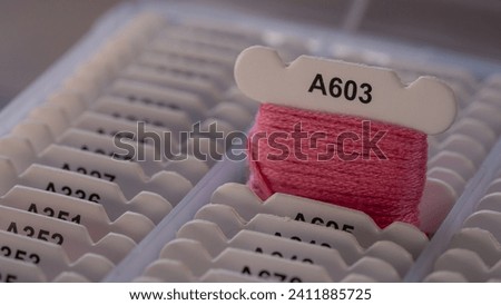 Choosing a Pink Floss Bobbin and Thread Piece in a Box Royalty-Free Stock Photo #2411885725