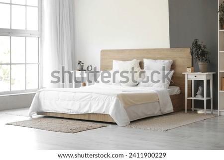 Interior of modern bedroom with white bed and alarm clock on bedside table Royalty-Free Stock Photo #2411900229