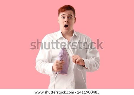 Shocked young man with electric iron on pink background