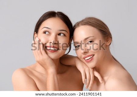Happy young women on grey background Royalty-Free Stock Photo #2411901141
