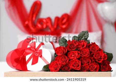 Bouquet of beautiful roses and heart-shaped gift boxes on table, closeup. Valentine's Day celebrations