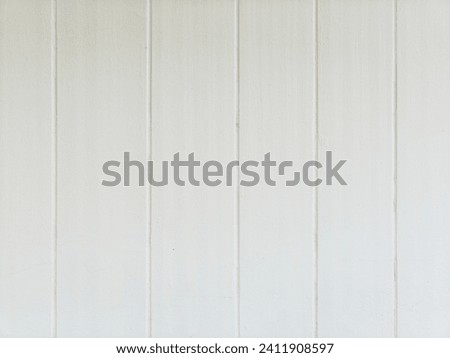 Cement wall is white with vertical grooves, used as a background for placing colorful things.