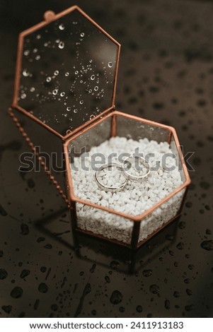 wedding rings in a glass box on a table in the rain
