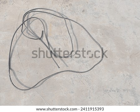 A pice of Black wire on the house roof in front of sunlight. Black wire pice have no spacific shape. Black wire have shadow in sunlight. Royalty-Free Stock Photo #2411915393
