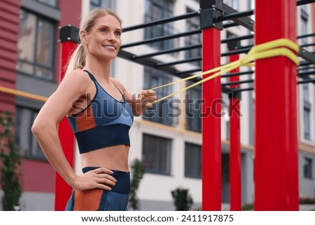 Athletic woman doing exercise with fitness elastic band at outdoor gym