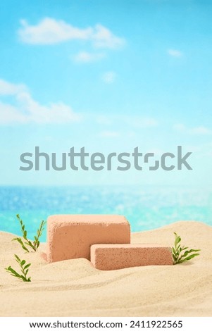 Two brick podiums decorated on sand beach with green grass. Empty space for design. Blue sea and blue sky for summer vacation concept. Vertical frame for social advertising