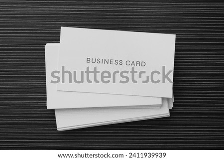 Stack of business cards on black wooden table, top view