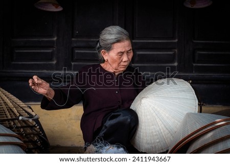 old woman making conical hats - Vietnamese name is Non la. Lang Chuong village, Hanoi city, Vietnam. Travel concept. Royalty-Free Stock Photo #2411943667