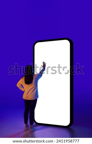 Young woman, student engaged in educational content on phone, suggesting interactive learning. Promoting educational apps or platforms. Concept of technology progress, delivery, network. Ad Royalty-Free Stock Photo #2411958777