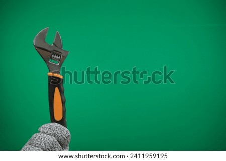 a worker, builder, repairman, handyman, hands with protection glove holding wrench advertising Green background chromakey free space