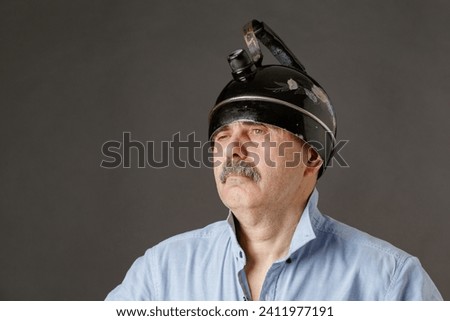 Portrait of a man with a grimace on his face and a teapot on his head
