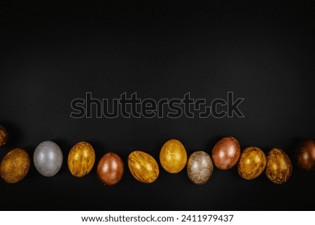 Golden and silver Easter eggs on black table background, easter background, top view