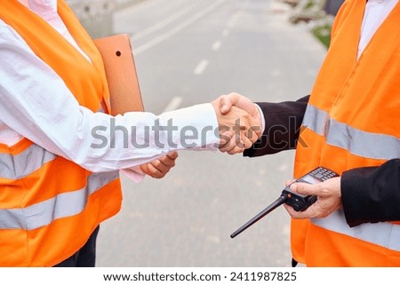 Construction staff in safety vests greeting one another outdoors