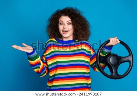 Photo of attractive young woman hold steering wheel shrug shoulder dressed stylish rainbow print clothes isolated on blue color background