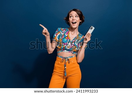 Photo of young woman surprised look novelty pointing finger showing instagram reels new trend using phone isolated on blue color background