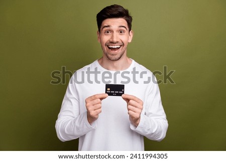 Photo of astonished cheerful man arms hold demonstrate plastic debit card isolated on khaki color background