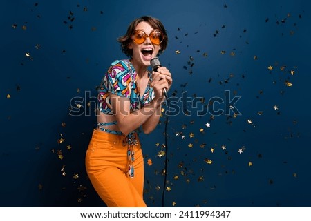 Photo portrait of lovely young lady singing mic party energetic wear trendy flared pants garment isolated on dark blue color background
