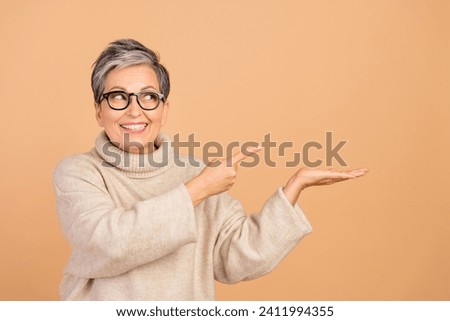 Photo of positive nice person beaming smile look indicate finger hand hold empty space isolated on beige color background