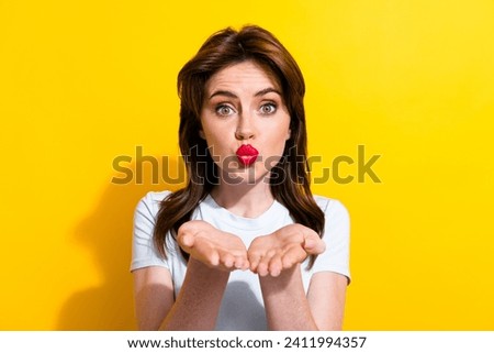 Portrait of good mood pretty girl with brunette hair wear white t-shirt sending air kiss to you isolated on yellow color background