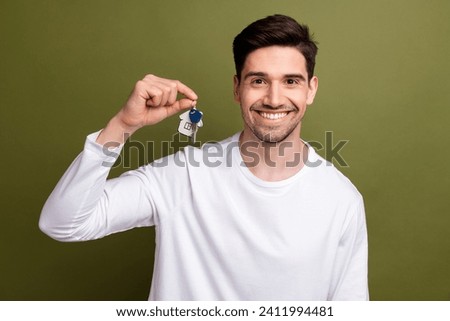 Photo of young optimistic happy man new owner apartments holding keys wearing white long sleeve isolated on khaki color background