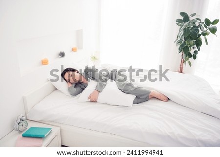 Photo portrait of lovely young lady lying bed sleep hug pillow dressed stylish gray sleepwear isolated on white bedroom indoor interior Royalty-Free Stock Photo #2411994941