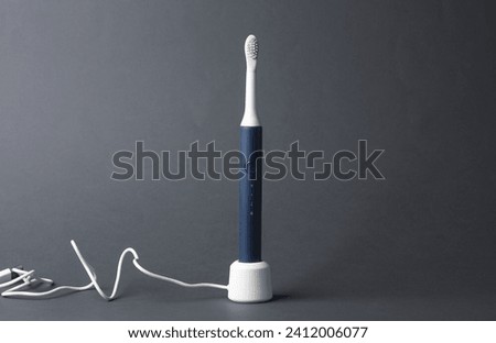 Modern smart ultrasonic toothbrush charging on dark gray background