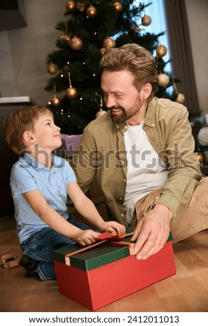 Father and son opening Christmas present box celebrating New Year in hotel
