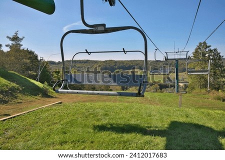 Chairlifts at ski resort in fall with no snow and lots of grass Royalty-Free Stock Photo #2412017683