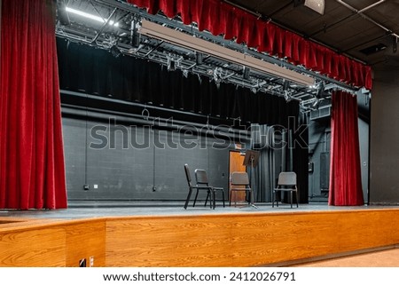 Photo of a new school stage, theater, auditorium, with gray seats, chairs.	