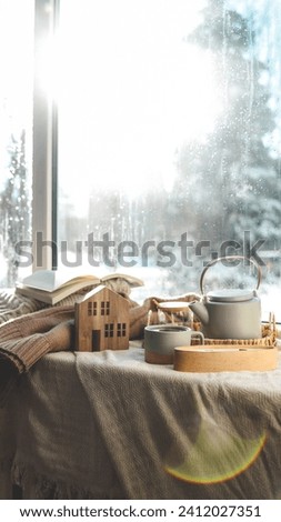 Cozy winter photo, stack of sweaters, book, tea and candle.