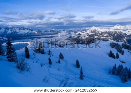 Scenic snow and white winter landscape with ski trail, mountains clouds lake and fresh powder snow taken at high altitude near Kirchberg and Kitzbuhel and the Brixental valley in the Austrian alps.