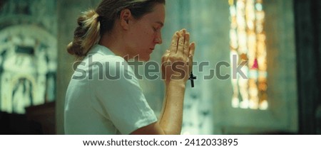 Woman folded hands in prayer in cathedral church. A sincerely believing girl prays to God for forgiveness of sins.