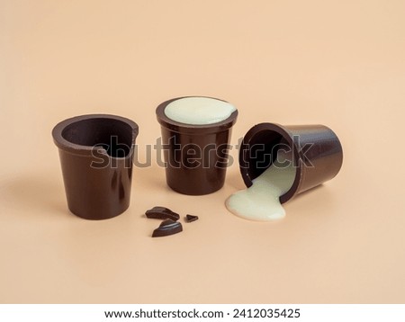 Chocolate cup filled with white pudding on an orange background. Chocolate cup close-up.